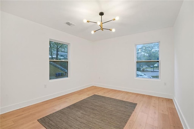 unfurnished room featuring a chandelier and hardwood / wood-style flooring