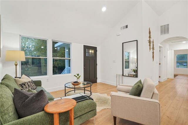 living room with light hardwood / wood-style floors and high vaulted ceiling