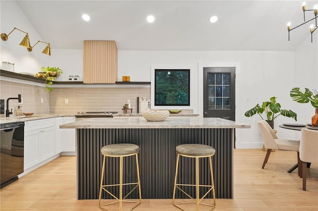 kitchen featuring a kitchen breakfast bar, white cabinetry, a center island, and light hardwood / wood-style flooring