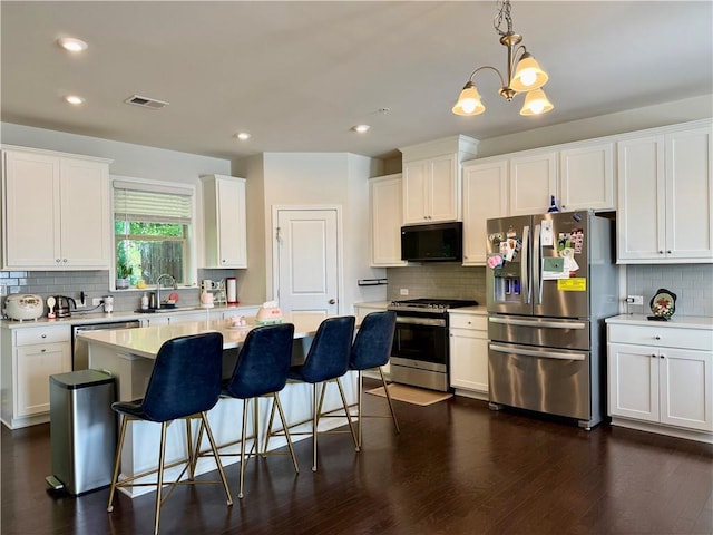 1452 Ridgebend Way SE, Mableton, GA 30126 - kitchen featuring appliances with stainless steel finishes, backsplash, white cabinetry, light countertops, and a breakfast bar area