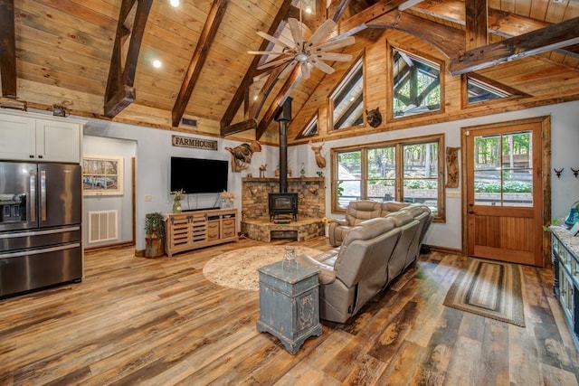 living room with wood ceiling, hardwood / wood-style flooring, high vaulted ceiling, beamed ceiling, and a wood stove