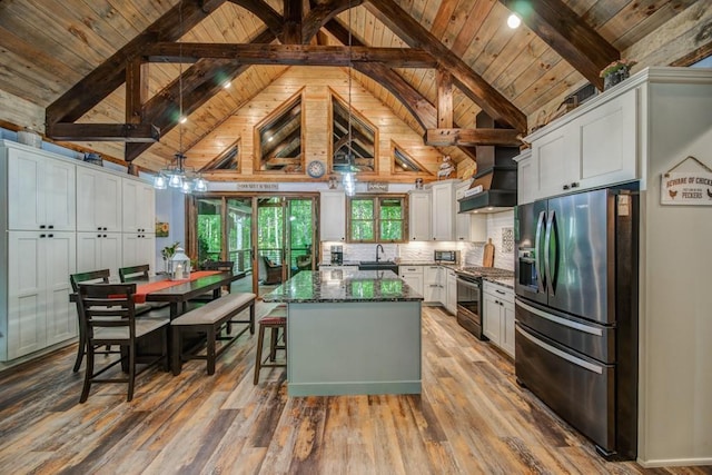 kitchen with white cabinets, appliances with stainless steel finishes, beam ceiling, and dark stone countertops