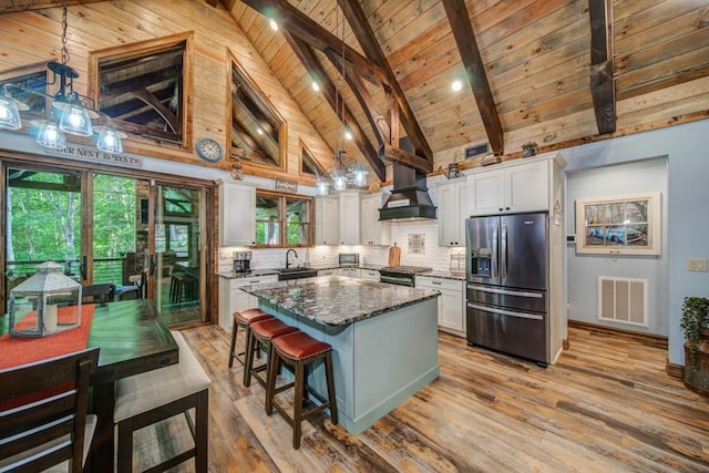 kitchen with appliances with stainless steel finishes, premium range hood, tasteful backsplash, dark stone counters, and white cabinetry