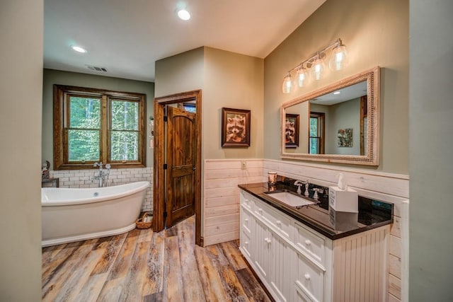 bathroom with vanity, wood-type flooring, and a tub