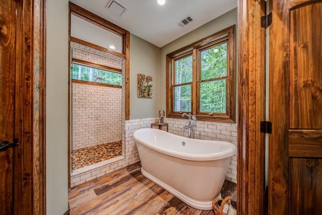 bathroom featuring hardwood / wood-style flooring, separate shower and tub, and tile walls