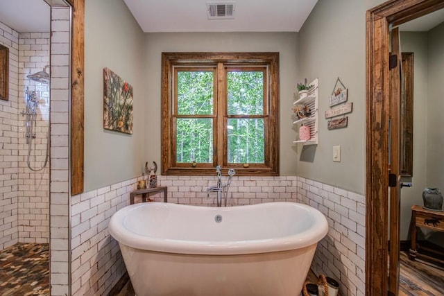 bathroom featuring tile walls and independent shower and bath