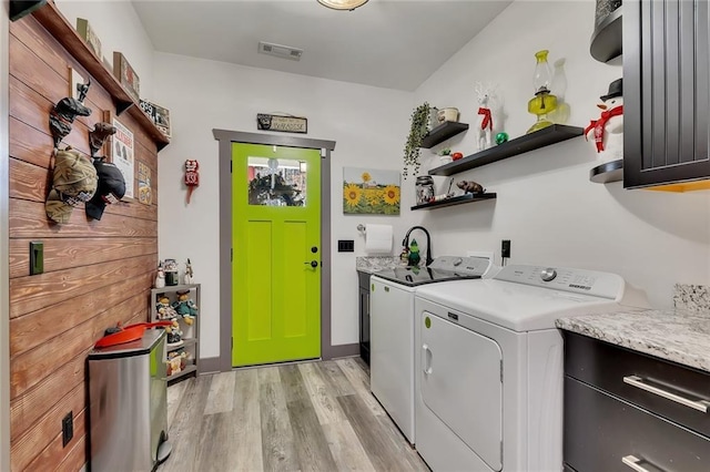 laundry area with separate washer and dryer, light hardwood / wood-style flooring, and cabinets