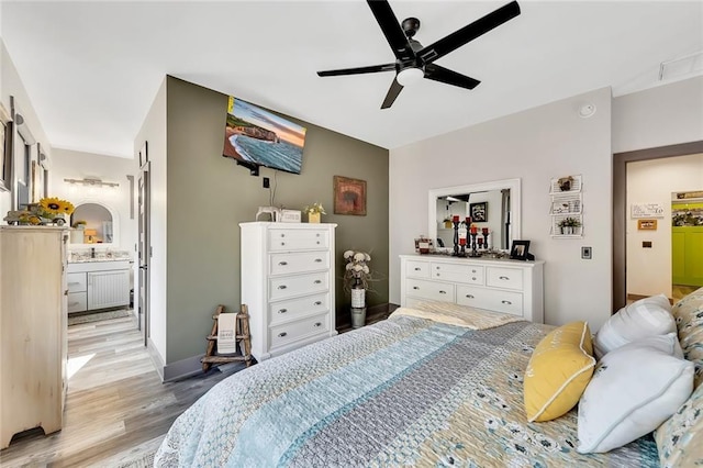 bedroom featuring connected bathroom, light hardwood / wood-style flooring, and ceiling fan