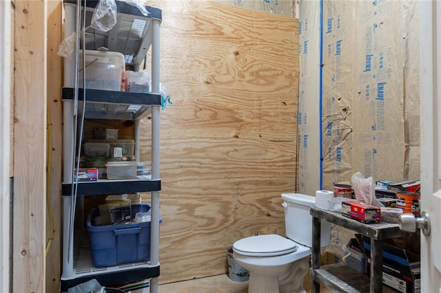 bathroom with wood walls and toilet