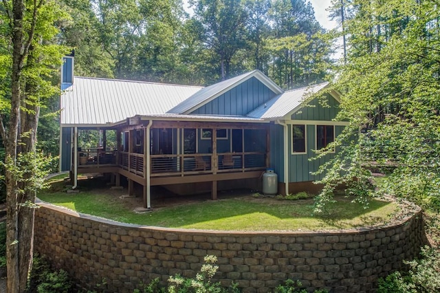 back of property with a sunroom, a yard, and a deck