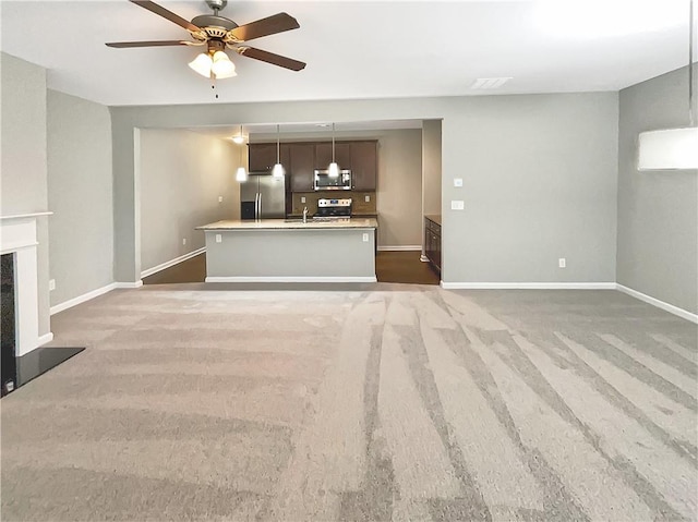 unfurnished living room featuring dark colored carpet, ceiling fan, and sink