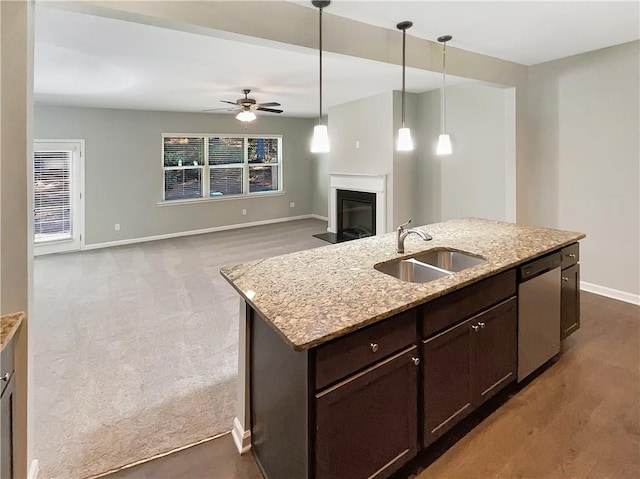 kitchen with dishwasher, light stone countertops, sink, and carpet floors