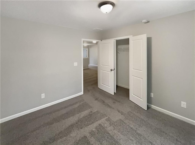 unfurnished bedroom with dark carpet and a closet