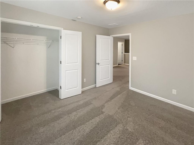 unfurnished bedroom with a closet and dark colored carpet