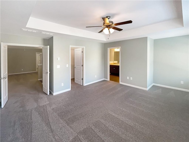 unfurnished bedroom featuring carpet flooring, a tray ceiling, ceiling fan, and ensuite bathroom