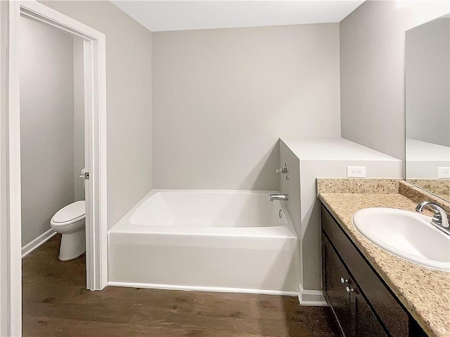 bathroom with vanity, toilet, wood-type flooring, and a bath