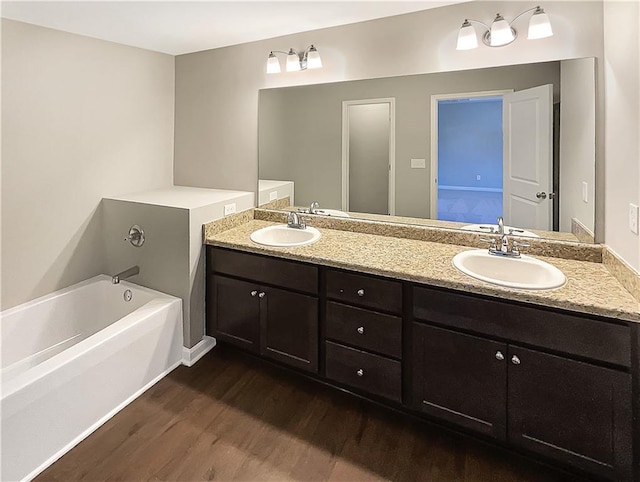 bathroom featuring hardwood / wood-style flooring, vanity, and a washtub