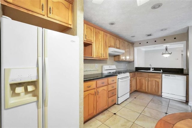 kitchen featuring white appliances, a sink, under cabinet range hood, dark countertops, and light tile patterned flooring