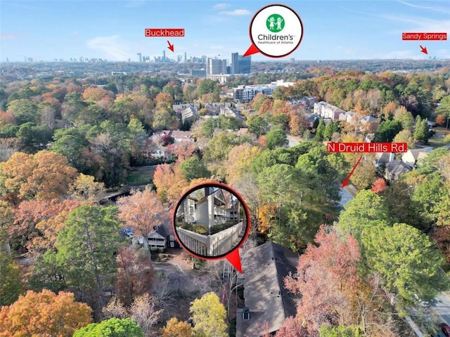 aerial view of property's location with nearby urban area and a heavily wooded area