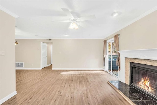 unfurnished living room with a premium fireplace, ornamental molding, baseboards, wood finished floors, and a ceiling fan
