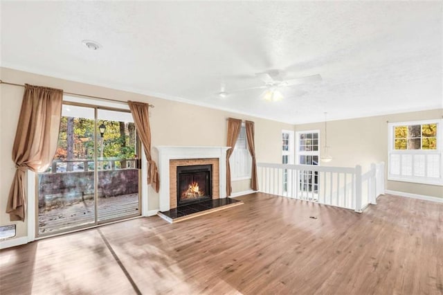 unfurnished living room with ceiling fan, wood finished floors, baseboards, a textured ceiling, and a fireplace