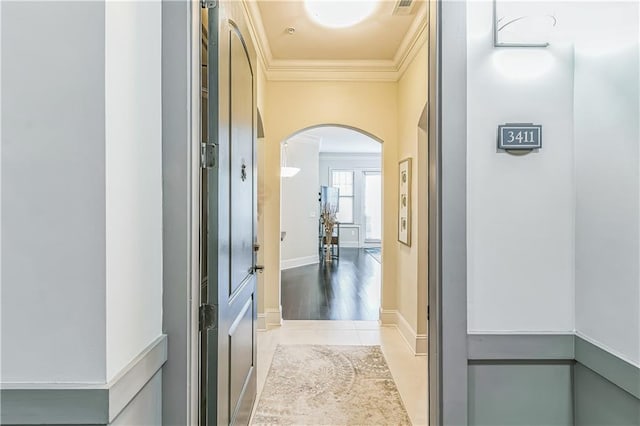 corridor with baseboards, arched walkways, ornamental molding, and tile patterned flooring