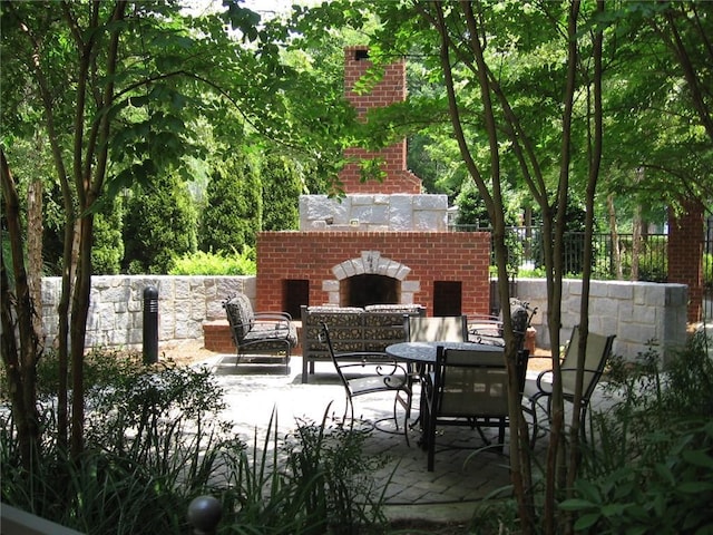 view of patio with fence and an outdoor brick fireplace