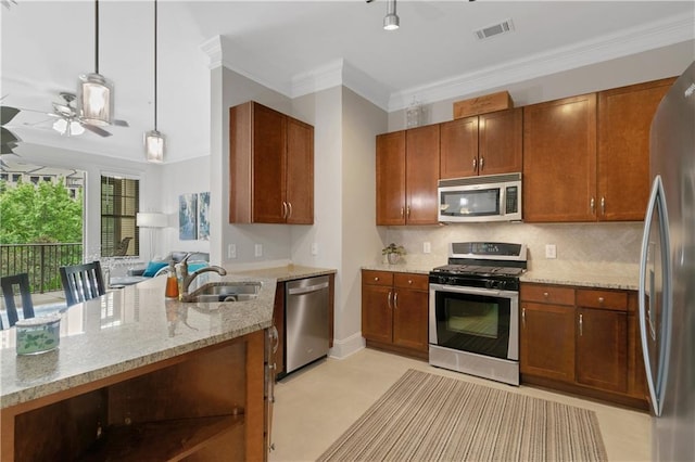 kitchen featuring sink, ornamental molding, decorative light fixtures, light stone counters, and stainless steel appliances