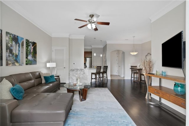 living area with ceiling fan, arched walkways, wood finished floors, and crown molding