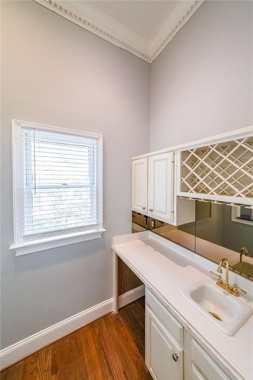 clothes washing area featuring dark hardwood / wood-style flooring, sink, and ornamental molding