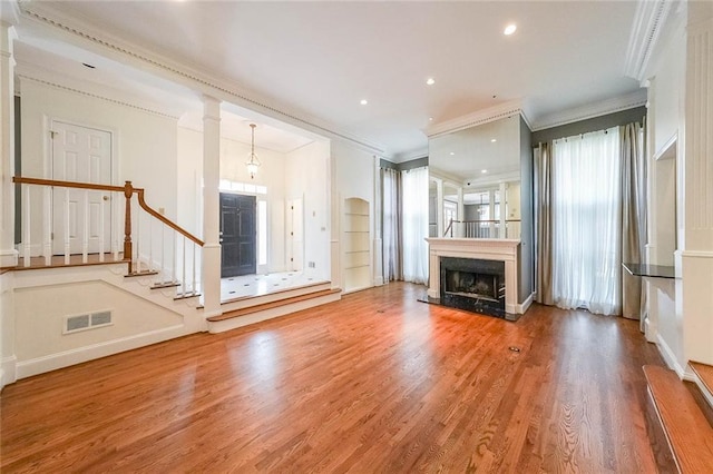 unfurnished living room featuring hardwood / wood-style flooring, ornamental molding, and a premium fireplace