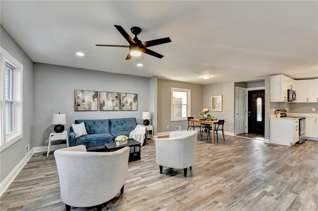 living room with plenty of natural light, light hardwood / wood-style floors, and ceiling fan