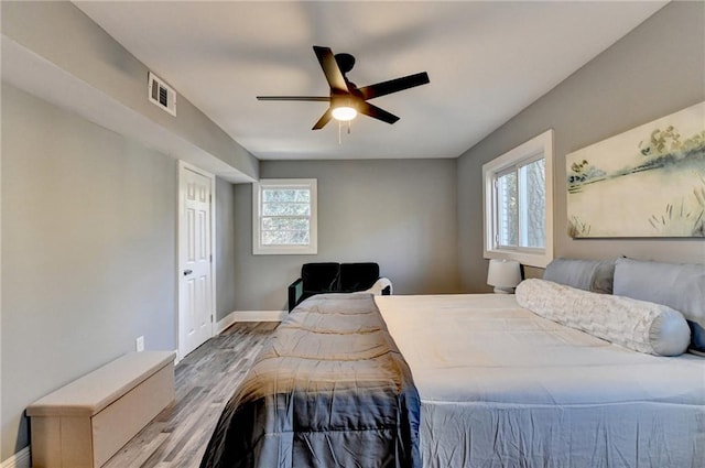 bedroom with ceiling fan, light hardwood / wood-style floors, and multiple windows