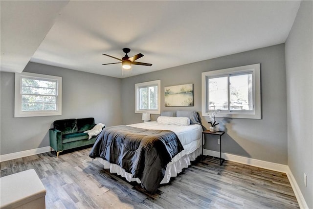 bedroom with ceiling fan, light hardwood / wood-style floors, and multiple windows