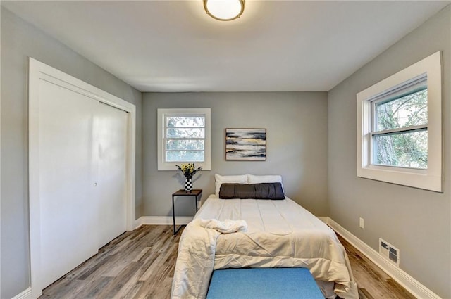 bedroom featuring hardwood / wood-style floors, a closet, and multiple windows