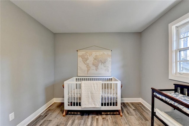 bedroom with wood-type flooring and a nursery area