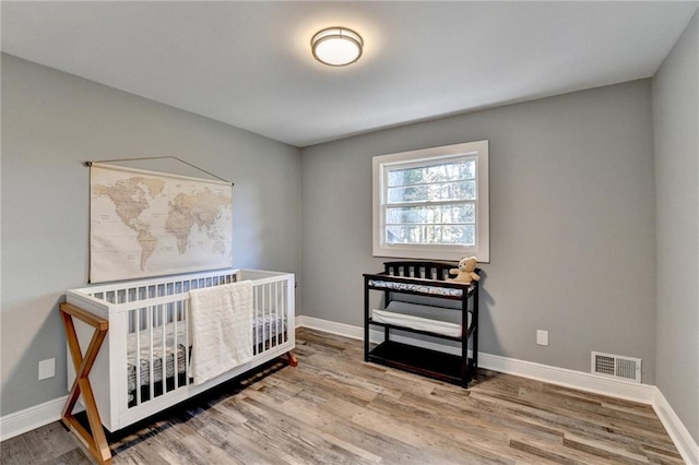 bedroom with hardwood / wood-style floors and a nursery area