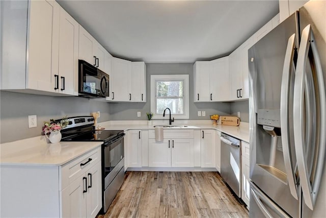 kitchen with sink, light wood-type flooring, white cabinetry, and stainless steel appliances