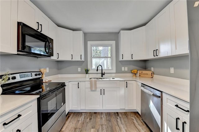 kitchen featuring sink, white cabinets, stainless steel appliances, and light hardwood / wood-style floors