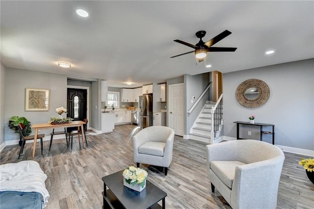 living room featuring ceiling fan, sink, and light wood-type flooring