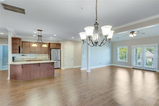 kitchen with light stone countertops, hardwood / wood-style floors, appliances with stainless steel finishes, and decorative light fixtures