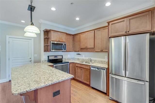 kitchen featuring sink, hanging light fixtures, light hardwood / wood-style flooring, appliances with stainless steel finishes, and ornamental molding