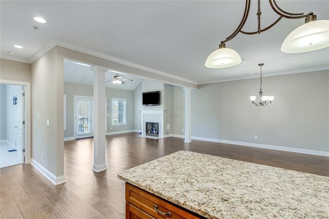 kitchen with light stone counters, hardwood / wood-style flooring, ceiling fan with notable chandelier, hanging light fixtures, and ornamental molding