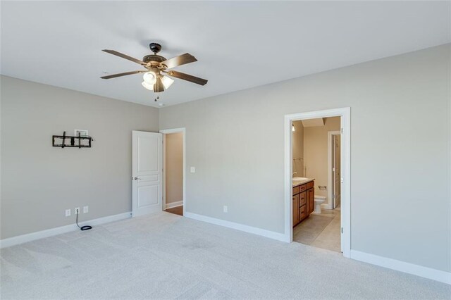 unfurnished bedroom with light carpet, ceiling fan, and ensuite bathroom