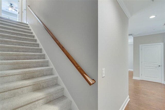 stairs with crown molding, hardwood / wood-style floors, and ceiling fan