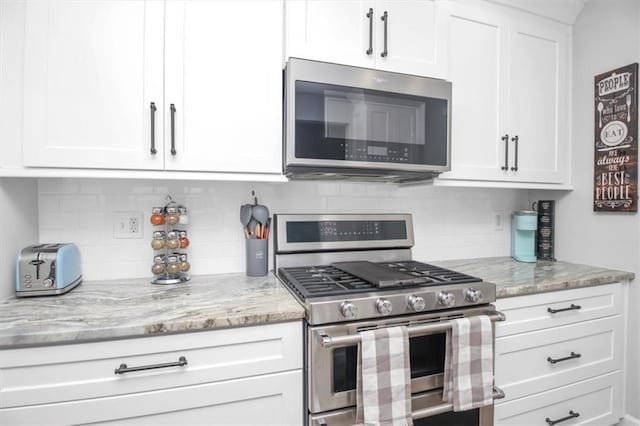 kitchen featuring stainless steel appliances, white cabinetry, tasteful backsplash, and light stone countertops