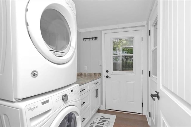 laundry area with cabinets, dark wood-type flooring, and stacked washer / dryer