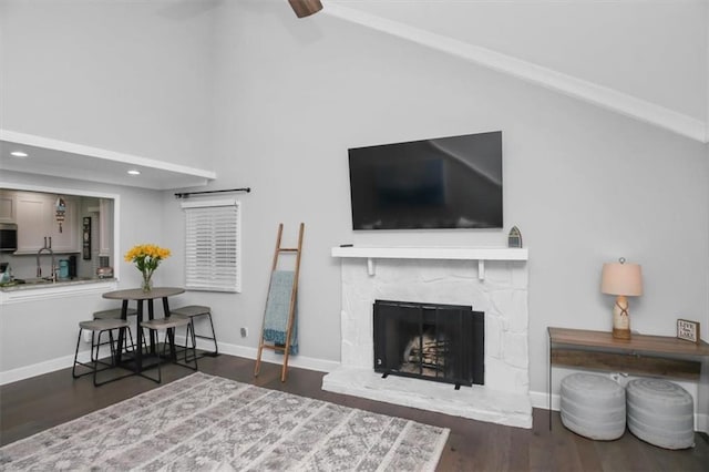 living room featuring a premium fireplace, dark hardwood / wood-style flooring, lofted ceiling, and sink