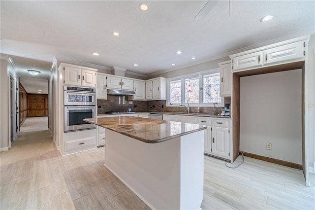 kitchen with white cabinetry, a center island, dark stone counters, and appliances with stainless steel finishes