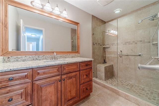 bathroom featuring vanity, tile patterned floors, a textured ceiling, and walk in shower